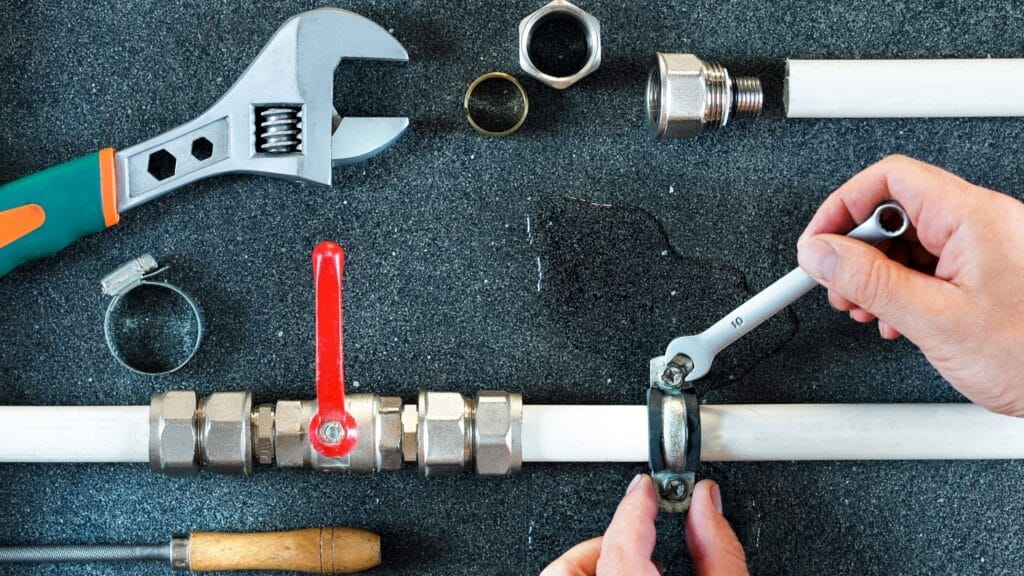 Plumber repairing a pipe valve with an adjustable wrench in Johnstown