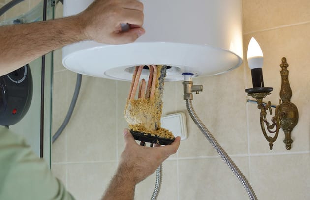 Technician removing mineral buildup from a water heater in Johnstown