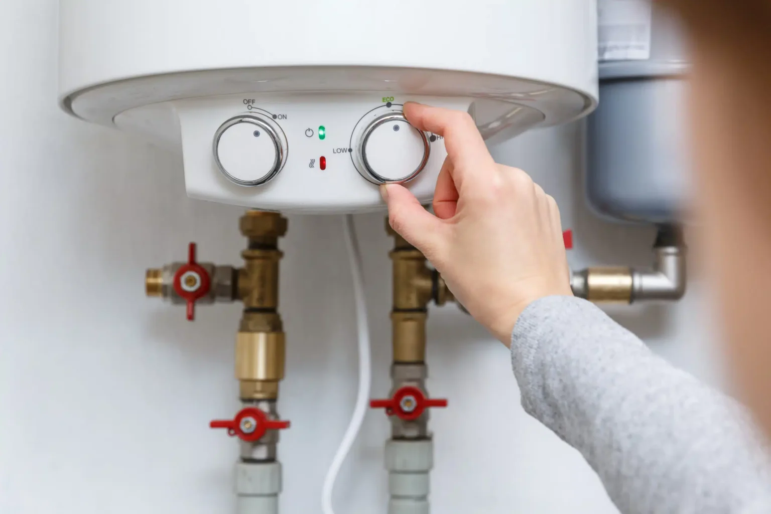 Homeowner adjusting the temperature controls on a water heater in Johnstown